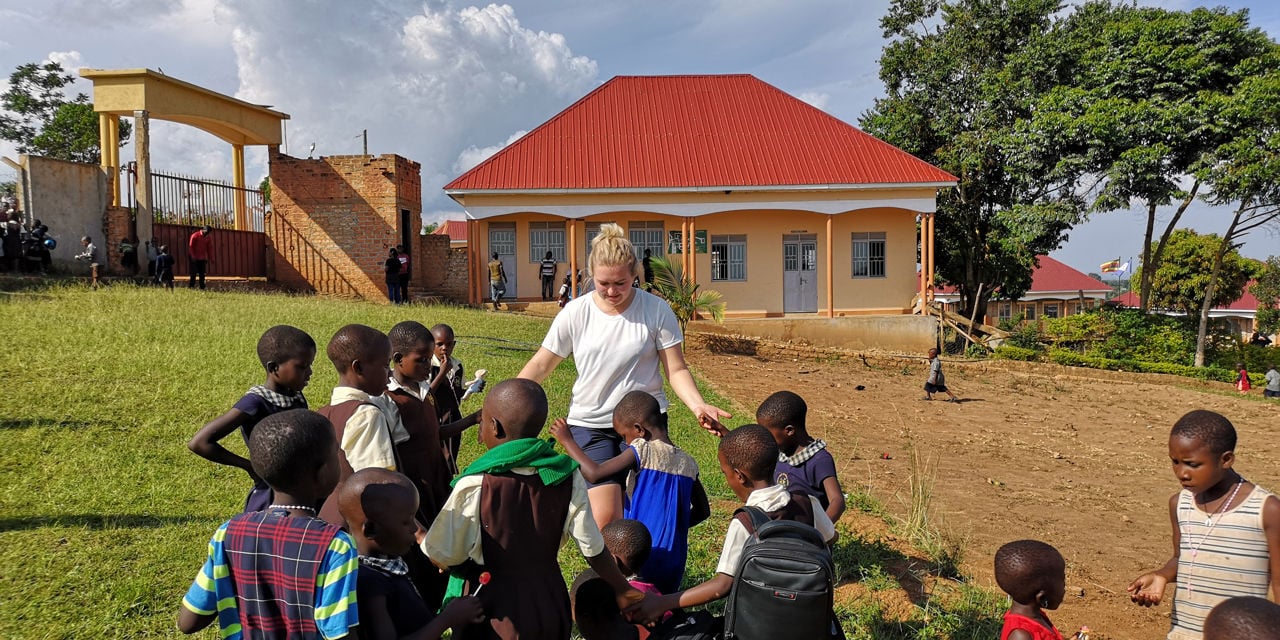 Bilde av elev fra Amalie Skram som står sammen med barnehjemsbarn i Uganda