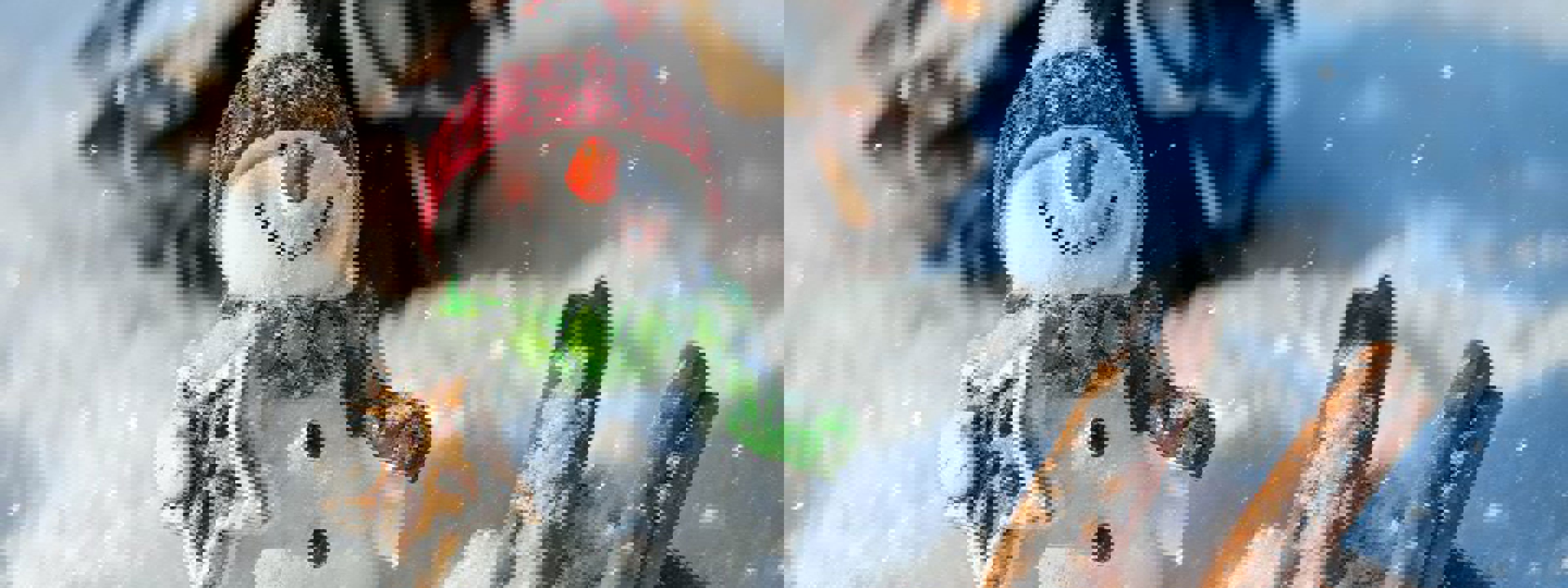 Bilde av snømann medlue og skjerf i snø-omgivelser som holder pepperkake. 